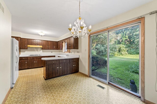7415 W Ute Ln, Palos Heights, IL 60463 - kitchen with white fridge with ice dispenser, light floors, light countertops, under cabinet range hood, and dark brown cabinetry