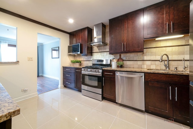 kitchen featuring decorative backsplash, stainless steel appliances, a sink, light stone counters, and wall chimney range hood