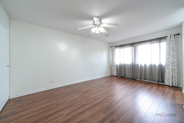 unfurnished room with a ceiling fan, dark wood-style floors, and baseboards
