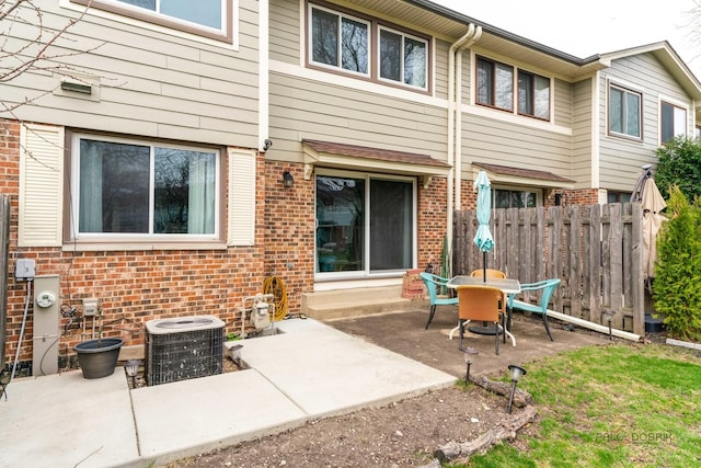 back of house with central air condition unit, brick siding, fence, and a patio area