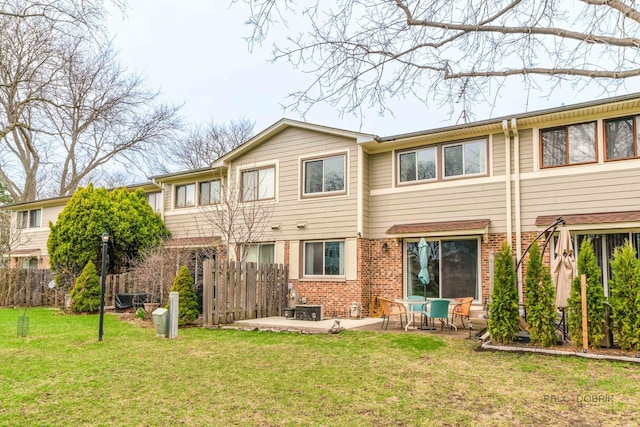 back of house with a lawn, fence, brick siding, and a patio