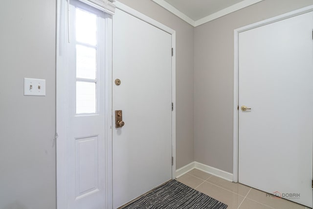 foyer entrance with light tile patterned floors, ornamental molding, and baseboards
