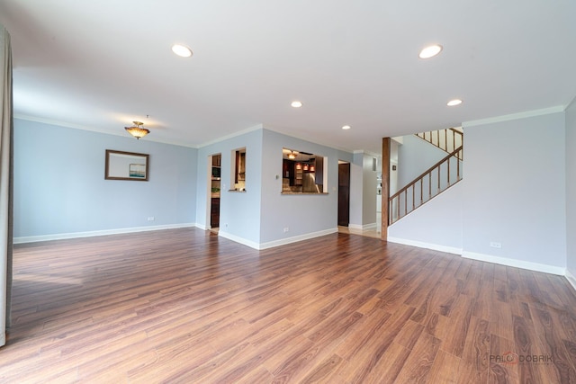 unfurnished living room with baseboards, crown molding, and wood finished floors