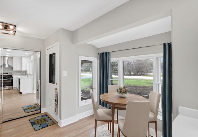 dining space with light wood-type flooring and baseboards