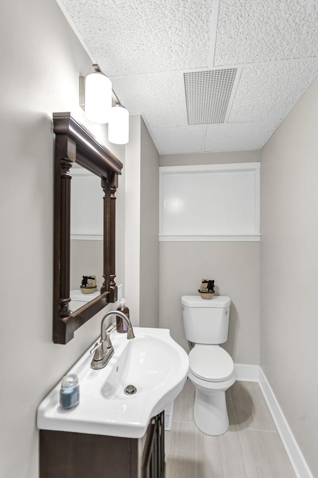 bathroom featuring toilet, vanity, baseboards, and visible vents
