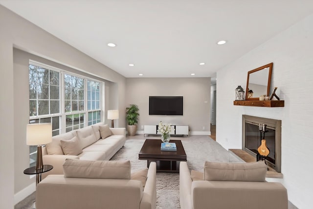 living area with a glass covered fireplace, recessed lighting, and baseboards