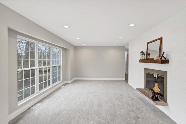 unfurnished living room featuring baseboards, a glass covered fireplace, carpet, and recessed lighting