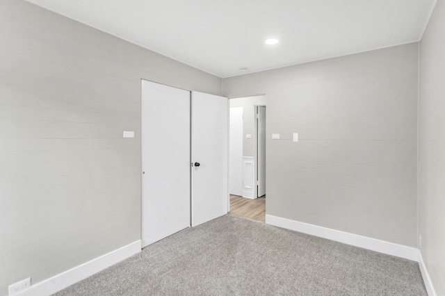 spare room with baseboards, recessed lighting, and light carpet