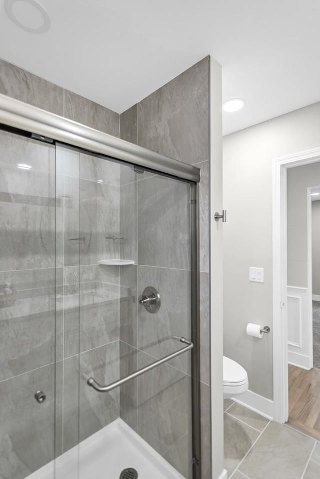 bathroom with toilet, a shower stall, and baseboards
