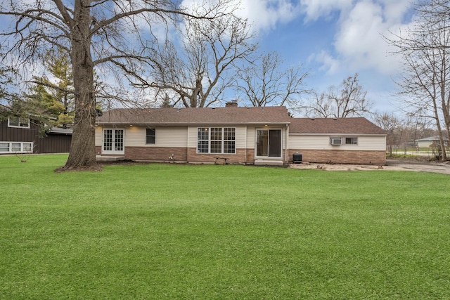 ranch-style home featuring brick siding, french doors, a front lawn, and a chimney