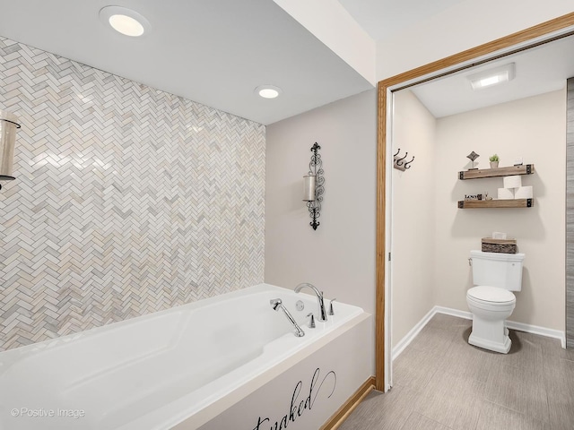 bathroom featuring baseboards, recessed lighting, toilet, and a bath