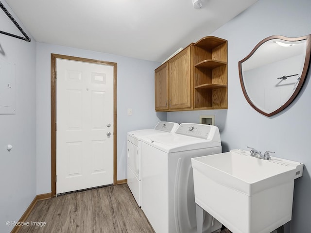 laundry room featuring washer and clothes dryer, a sink, light wood-type flooring, baseboards, and cabinet space