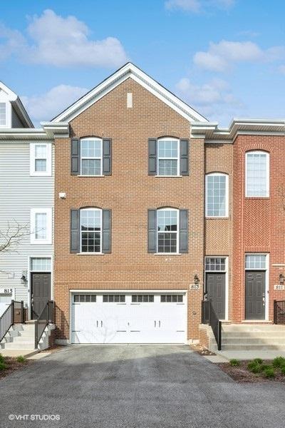 view of property with brick siding, an attached garage, and aphalt driveway