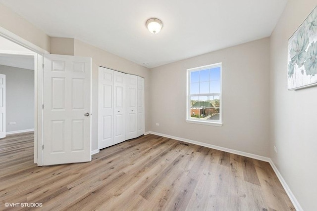 unfurnished bedroom with a closet, wood finished floors, and baseboards