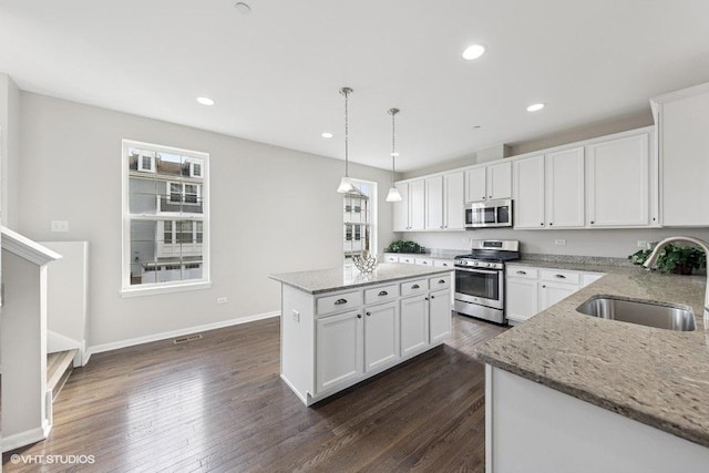 kitchen featuring light stone counters, white cabinetry, stainless steel appliances, and a sink