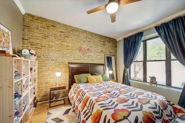 bedroom featuring wood finished floors, a ceiling fan, and brick wall
