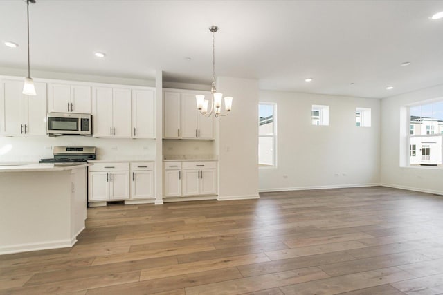 kitchen featuring white cabinetry, stainless steel appliances, a notable chandelier, and light wood finished floors