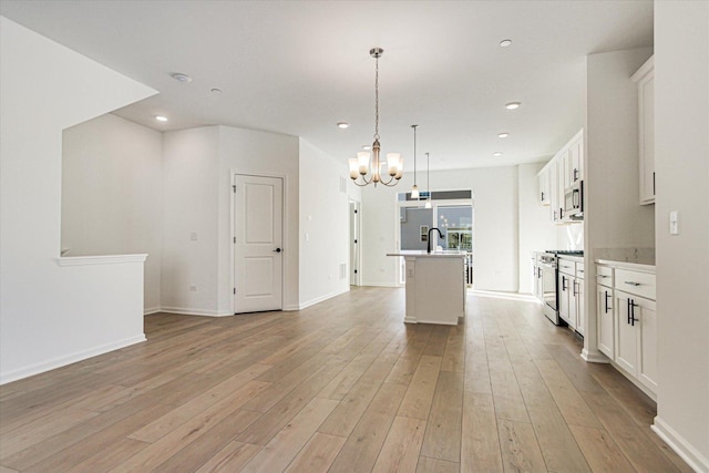kitchen featuring a center island with sink, a notable chandelier, appliances with stainless steel finishes, and light wood-style floors