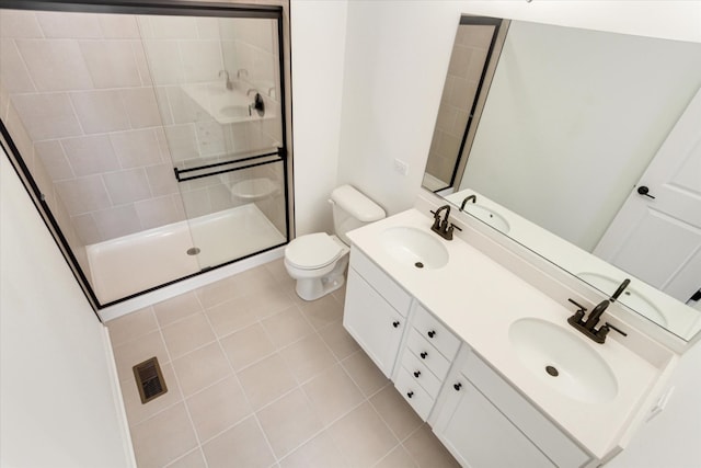 bathroom with toilet, a sink, tiled shower, and visible vents
