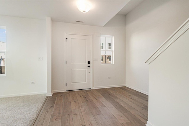 entryway with baseboards, visible vents, and wood finished floors