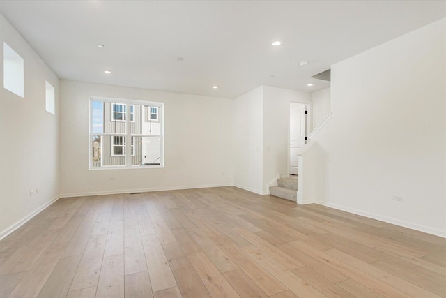 spare room featuring light wood-style flooring, baseboards, stairs, and recessed lighting