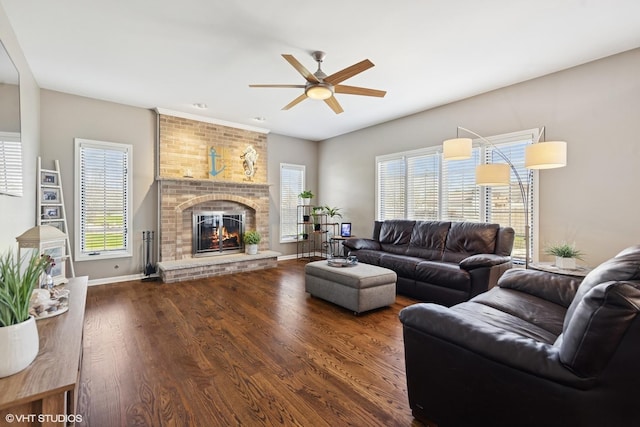 living area with a fireplace, wood finished floors, a ceiling fan, and baseboards