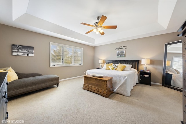 bedroom with light carpet, a ceiling fan, baseboards, and a raised ceiling