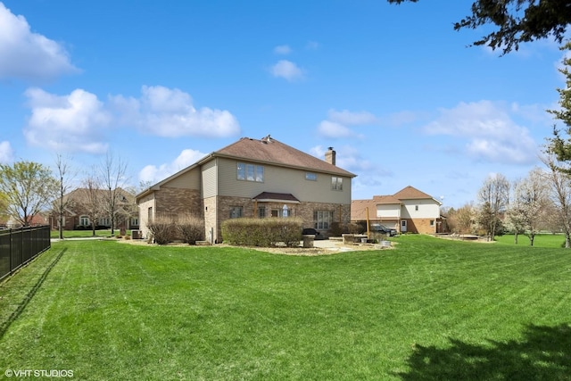 back of property with a lawn, fence, a chimney, and a patio