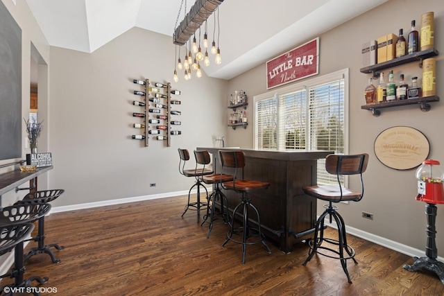 bar with lofted ceiling, baseboards, a bar, and dark wood finished floors