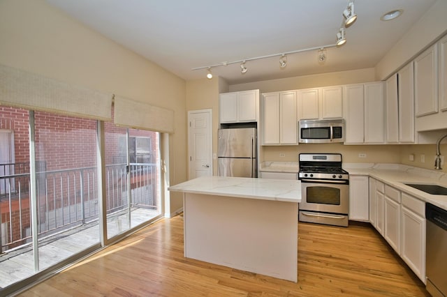 353 E Eastgate Pl, Chicago, IL 60616 - kitchen with appliances with stainless steel finishes, a kitchen island, light wood-style floors, white cabinetry, and light stone countertops