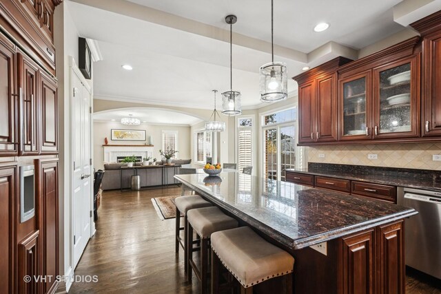 kitchen featuring arched walkways, open floor plan, dark wood-style floors, stainless steel dishwasher, and decorative backsplash