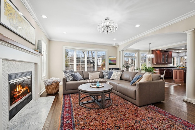 living area featuring a chandelier, a fireplace, dark wood-type flooring, and a wealth of natural light