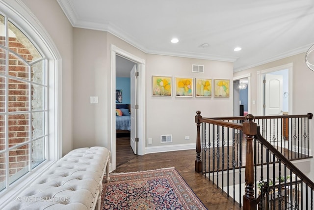 corridor featuring crown molding, wood finished floors, visible vents, and an upstairs landing