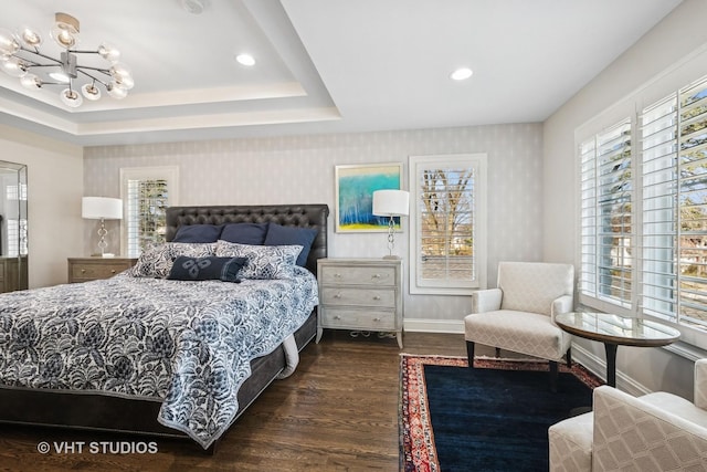 bedroom featuring wallpapered walls, a tray ceiling, an inviting chandelier, and wood finished floors