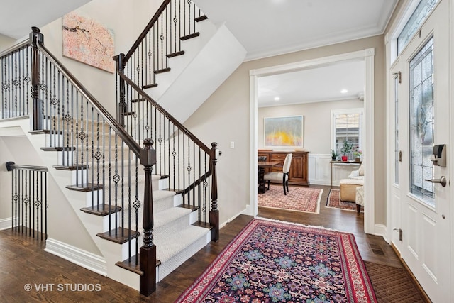 foyer with crown molding, baseboards, wood finished floors, and stairs