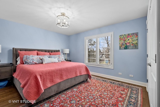 bedroom with baseboards, a chandelier, and wood finished floors