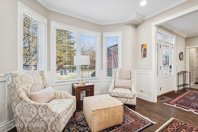 living area featuring a decorative wall, ornamental molding, a wainscoted wall, and wood finished floors