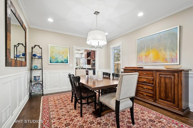 dining room with crown molding, an inviting chandelier, dark wood finished floors, and wainscoting