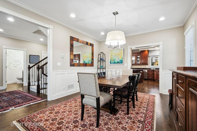 dining room featuring crown molding, a decorative wall, dark wood-style flooring, and stairway
