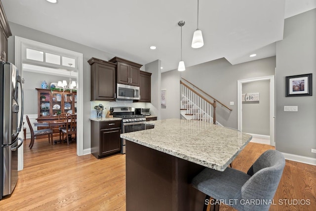 2793 Nicole Cir, Aurora, IL 60502 - kitchen featuring dark brown cabinets, light stone counters, a breakfast bar, light wood-style flooring, and stainless steel appliances
