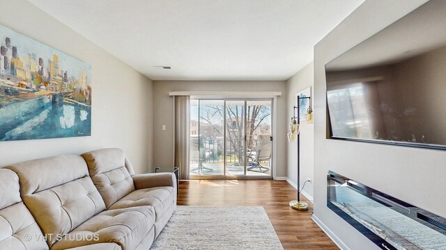 living room with visible vents, baseboards, and wood finished floors