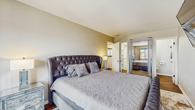 bedroom featuring baseboards, ensuite bathroom, and wood finished floors