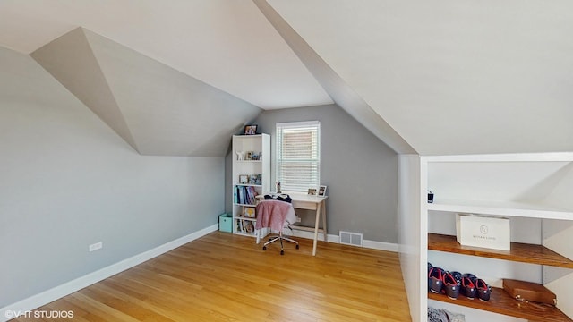 office space with wood finished floors, baseboards, lofted ceiling, and visible vents