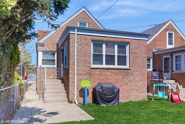 bungalow-style home with a front yard, fence, and brick siding