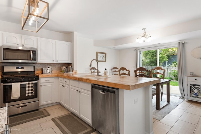 1704 Walnut Park Ln, Aurora, IL 60504 - kitchen featuring appliances with stainless steel finishes, a sink, a peninsula, a chandelier, and white cabinetry
