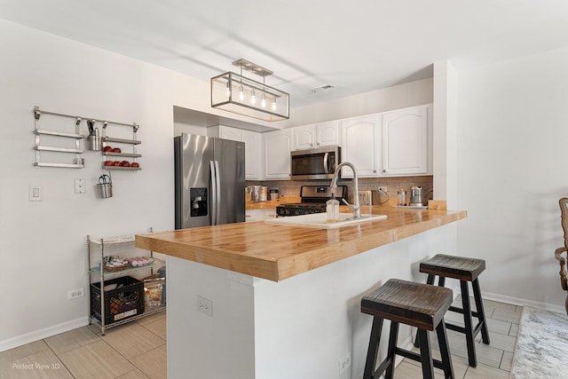 1704 Walnut Park Ln, Aurora, IL 60504 - kitchen with appliances with stainless steel finishes, a breakfast bar, white cabinets, decorative backsplash, and a peninsula