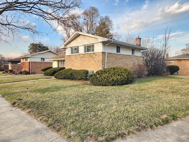 view of property exterior with a chimney, brick siding, and a yard