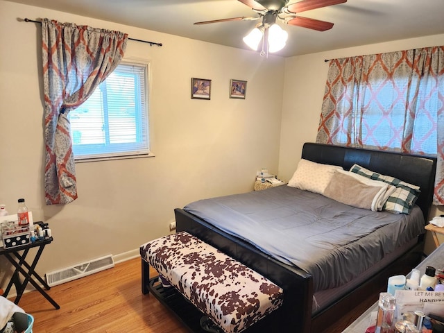 bedroom featuring baseboards, visible vents, light wood-style floors, and a ceiling fan