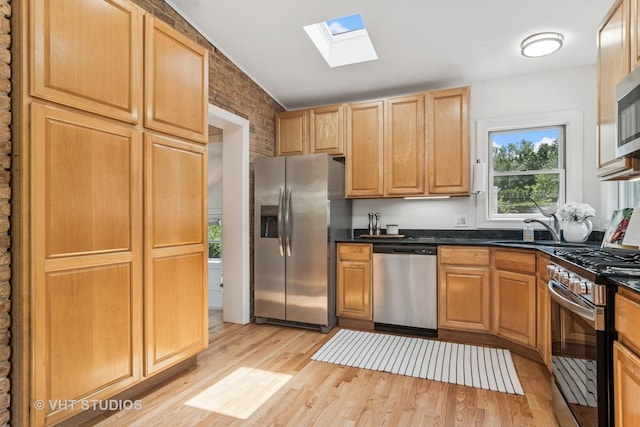 212 N Russel St, Mount Prospect, IL 60056 - kitchen featuring appliances with stainless steel finishes, a skylight, light wood-style floors, dark countertops, and brick wall