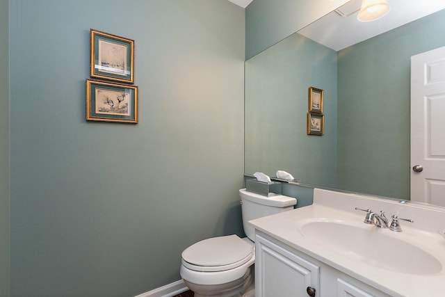 bathroom with baseboards, toilet, and vanity